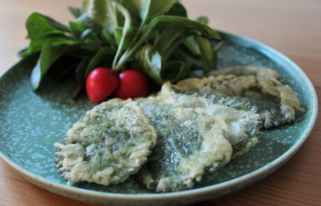 gebackene Brennnesselblätter in Tempura Teig auf einem grünen Teller