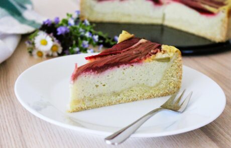 ein Stück veganer Käsekuchen mit Rhabarber auf einem weißen Teller