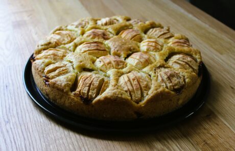 ein ganzer, runder apfelkuchen auf einem holztisch