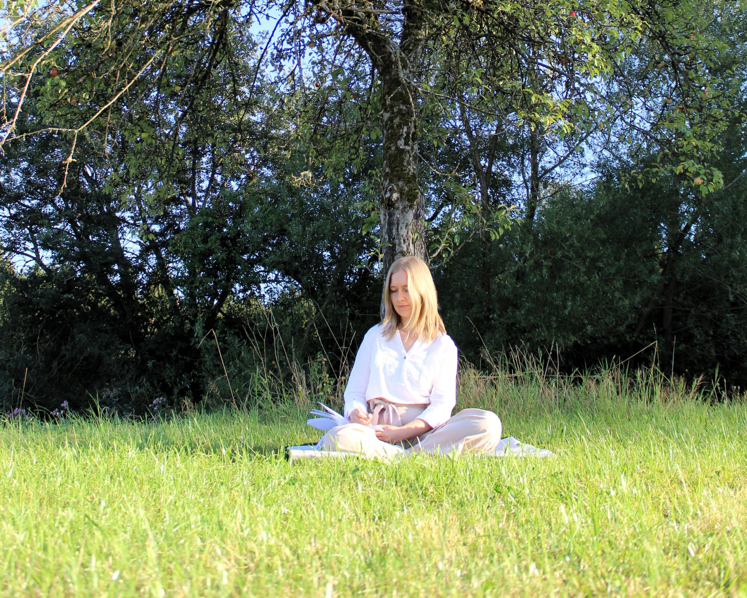 radikale Akzeptanz, Melissa Müller beim Journaln in der Natur auf einer Wiese vor einem großen Baum